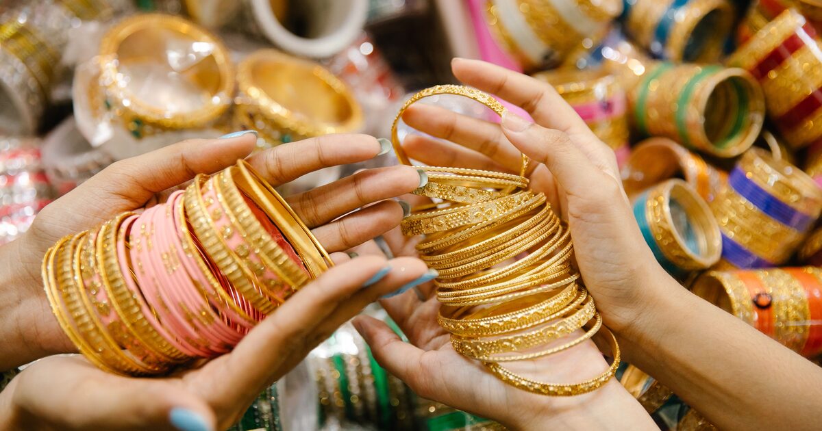 Hands holding stacks of gold bangles