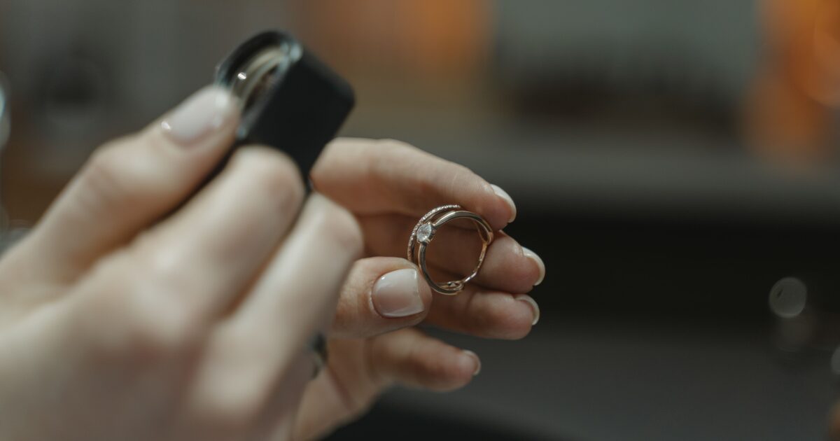 A jeweller holding a diamond ring beside a loupe