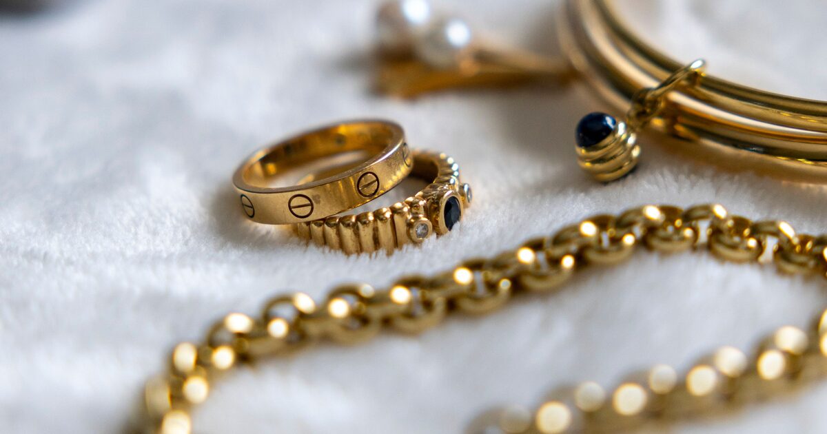 An assortment of gold rings and a gold chain on a soft light background
