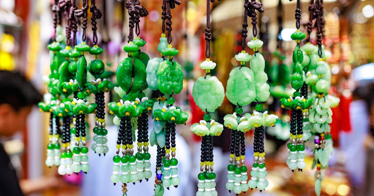 Carved green jade pendants and beaded tassels displayed at a jewelry market