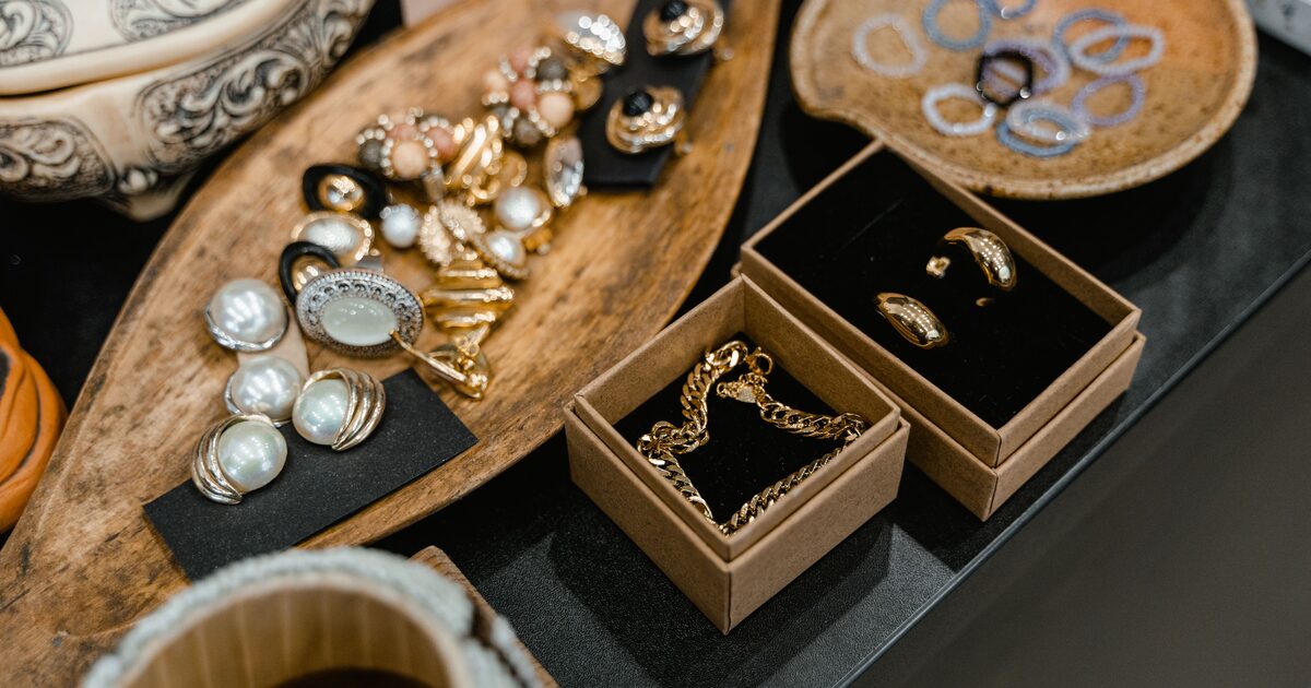 Assorted old jewelry sorted onto a tray and into small boxes, with a gold chain and pearl earrings